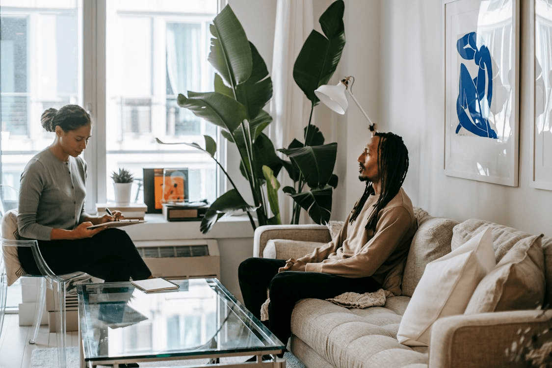 Two counselors in a bright living room consulting on session notes